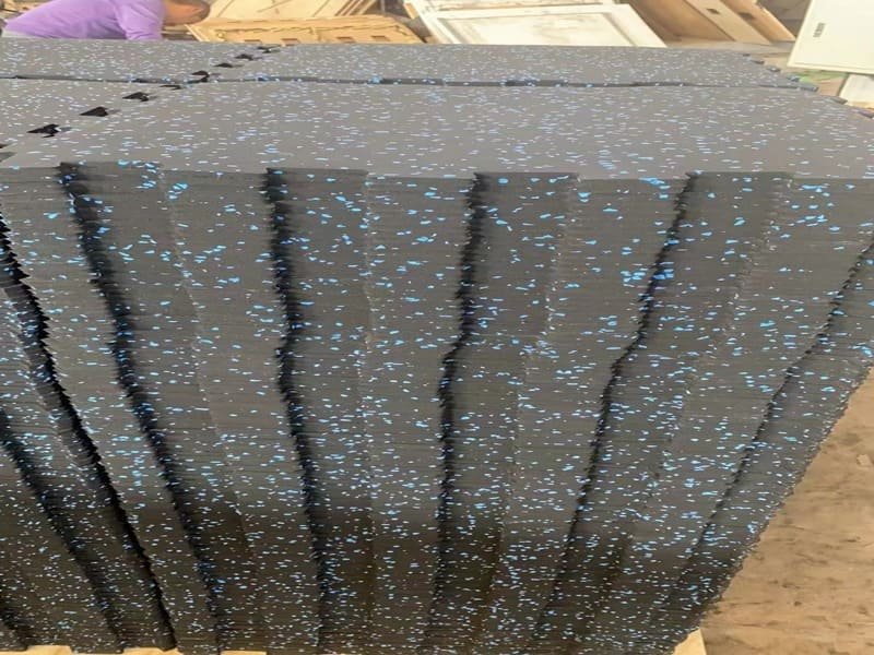 A person using a rubber mallet to gently tap interlocking mat seams together for a tight fit.